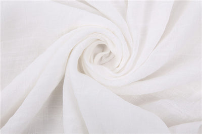 a close up of a white blanket on a bed 