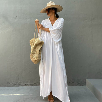 a woman in a white dress is talking on a cell phone 