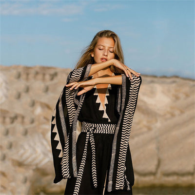 a woman standing on a beach holding a cell phone 