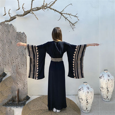 a woman standing next to a white vase 