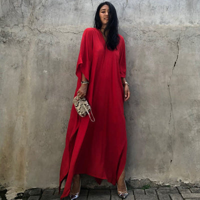 a woman in a red dress standing on a sidewalk 